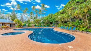 A swimming pool with lounge chairs and a building in the background. - Molokai condo Pool/Spa, 2 bedrooms/2 bathrooms. Walking distance to the beach.  (Maunaloa)