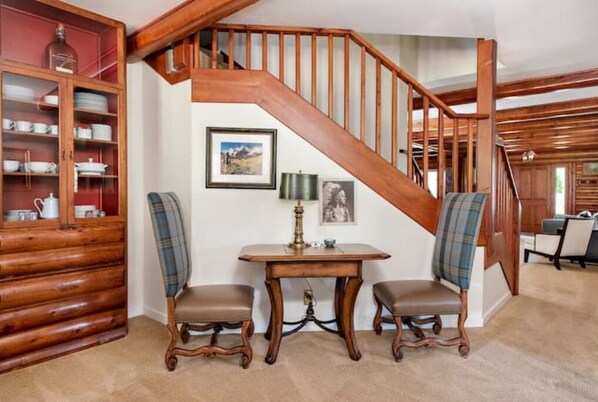 A wooden staircase with a view of a dining area below, featuring a table with chairs and a cabinet with dishes. - Historic Log Cabin- Downtown Basalt, Aspen Skiing Nearby, Gold Medal Fishing (Basalt)