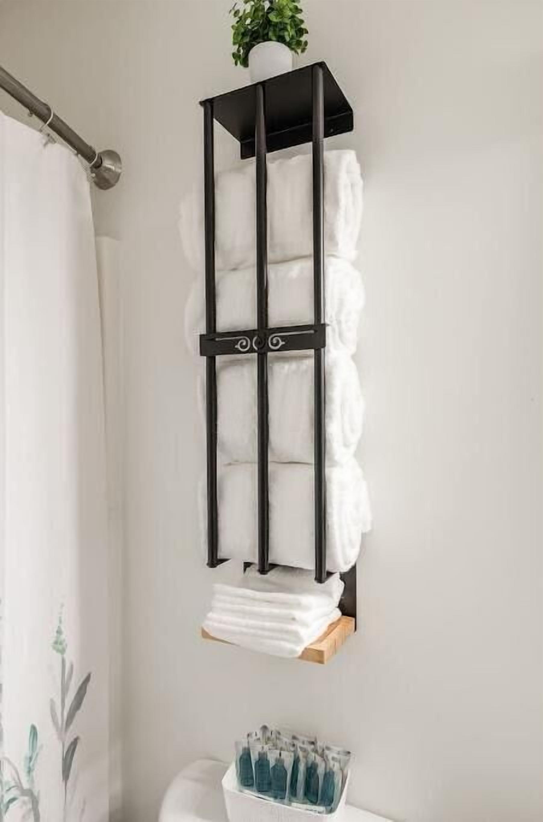 A bathroom with a towel rack holding several white towels, a small potted plant, and a basket of toiletries.
