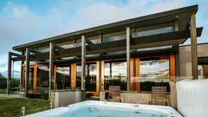 A modern building with a hot tub and outdoor seating. - Mt Gold Retreat - Tennis court - Hot Tub (Wanaka)