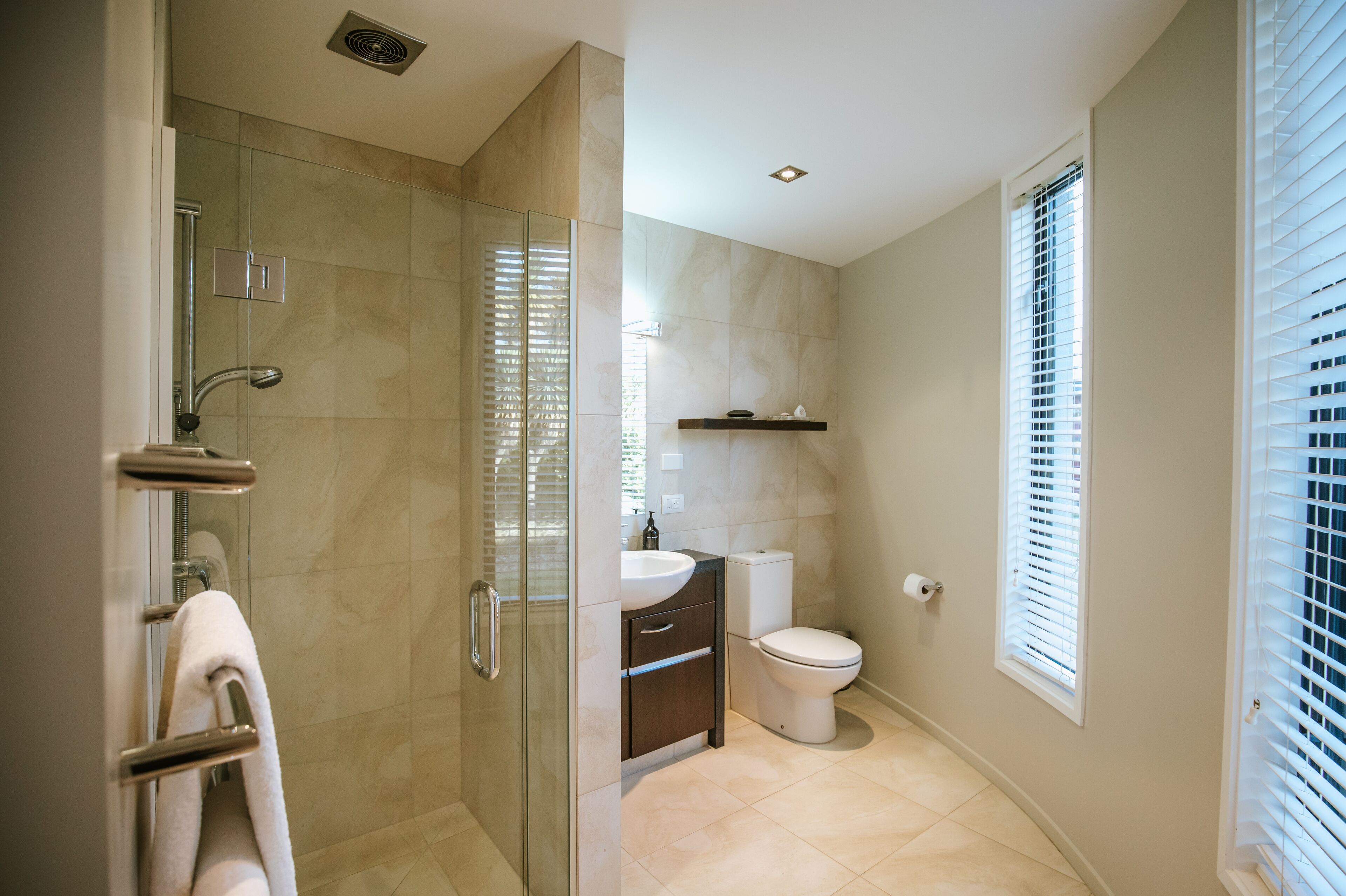A modern bathroom with a glass-enclosed shower, a toilet, and a sink.