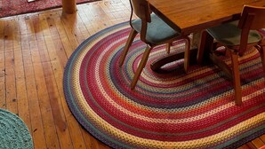 Ein gemütliches Blockhauss-Interieur mit einem Holzesstisch, bunten Webteppichen und einem blauen Sofa.