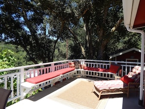A covered outdoor seating area with white railings, red cushions, and wicker furniture.