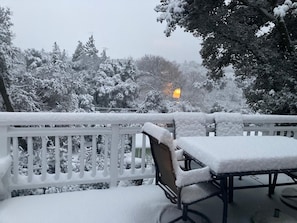 A snow-covered outdoor area with a white fence, a bench, and a table.