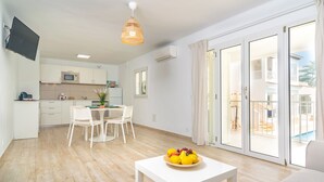 Ein modernes Apartment mit Küche, Essbereich und einem Balkon mit Blick auf einen Pool.