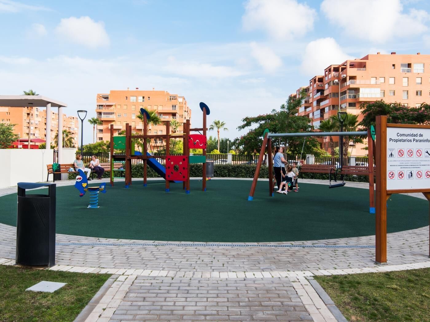 Un parque infantil con columpios, tobogán y estructuras para escalar.