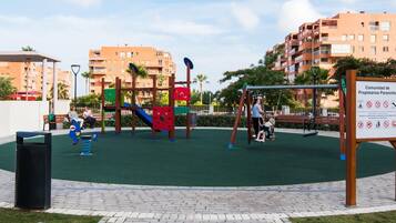Un parque infantil con columpios, tobogán y estructuras para escalar.