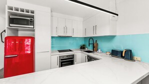 A modern kitchen with white cabinets, a red refrigerator, a microwave, a sink, and a toaster. - 5 mins walk to Hastings Street (Noosa)