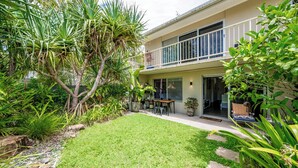 A two-story house with a balcony, a grassy backyard, and various plants. - 5 mins walk to Hastings Street (Noosa)