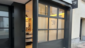 Ein modernes Gebäude mit einer großen Glasdoor, einem Schild mit der Aufschrift "espai 58" und einer kleinen Außenfläche mit einer Fußmatte.