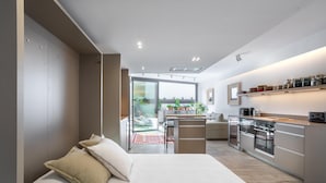 Ein modernes Schlafzimmer mit einem großen Bett, einem kleinen Schreibtisch und einer Küchenzeile.
