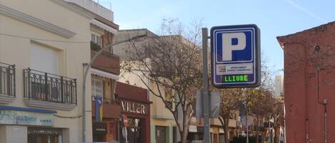 Escena callejera con una señal de estacionamiento, una clínica dental y un edificio con un letrero que dice 'VILLER'.