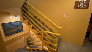 Eine Treppe mit gelben Geländern, ein Bild an der Wand und ein Schild mit der Aufschrift 'RAIN BED & BREAKFAST'.