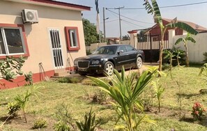 Un quartier résidentiel où une voiture noire est garée devant une maison à la façade rouge et blanche.