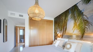 A bedroom with a large bed, a wooden wardrobe, a hanging light fixture, and a beach mural on the wall. - 16Benalmádena Cibeles, Pool View, Terrace, Golf (Benalmádena)