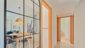 A modern living room with a dining area, featuring a glass partition, wooden furniture, and a hanging light fixture. - 16Benalmádena Cibeles, Pool View, Terrace, Golf (Benalmádena)