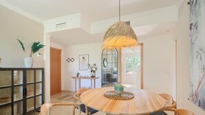 A dining area with a round wooden table, four wicker chairs, a hanging light fixture, and a potted plant. - 16Benalmádena Cibeles, Pool View, Terrace, Golf (Benalmádena)