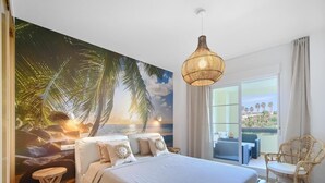A bedroom with a large bed, a view of the sea through a window, a hanging light fixture, and a wicker chair. - 16Benalmádena Cibeles, Pool View, Terrace, Golf (Benalmádena)
