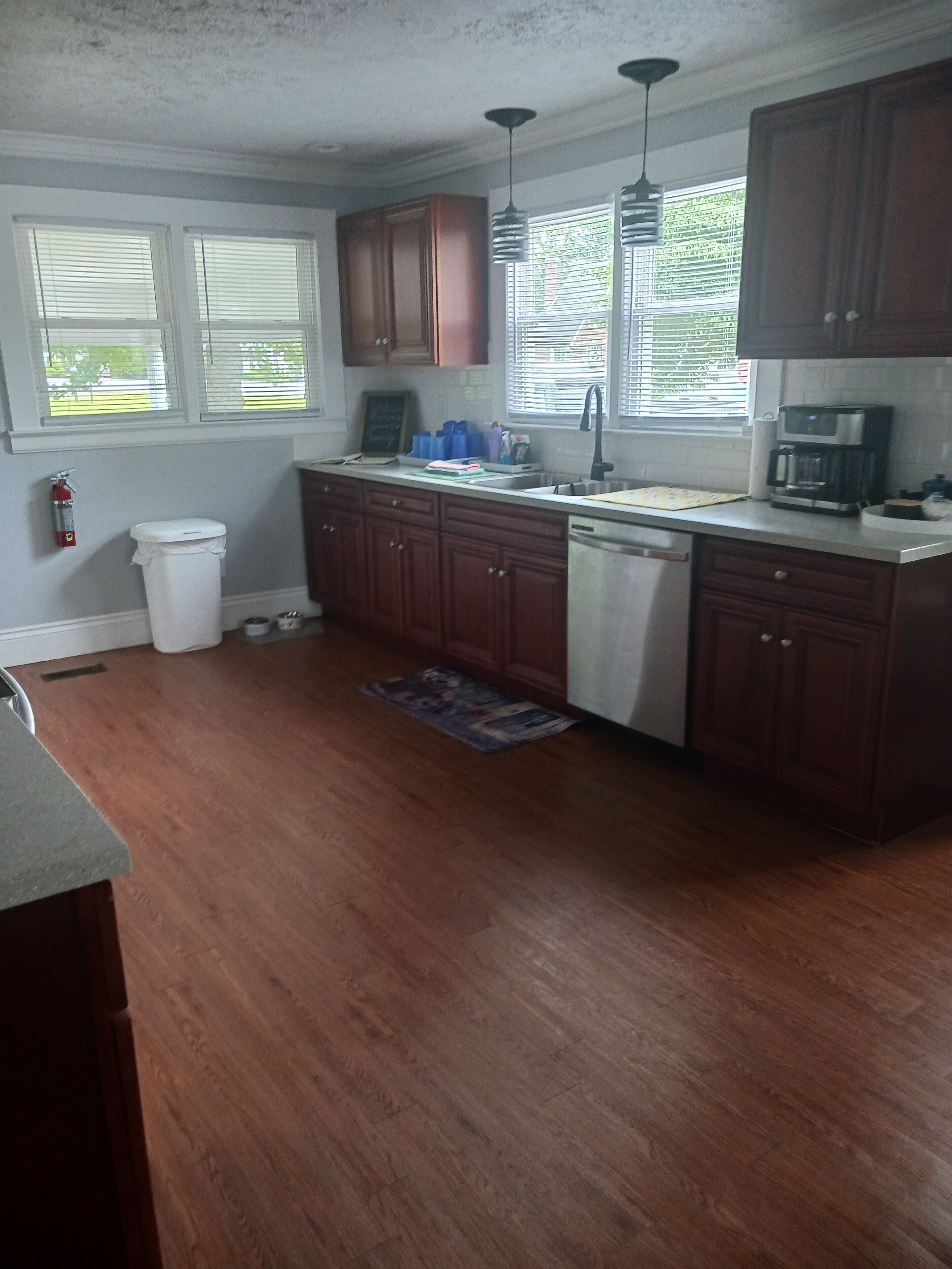 A kitchen with wooden cabinets, a stainless steel dishwasher, and a coffee maker.