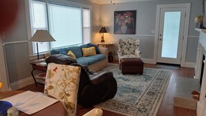 A living room with a sofa, armchair, rug, and a ceiling fan.