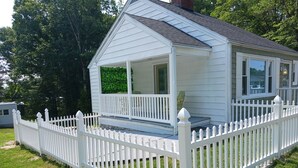 A small, single-story house with a white exterior and a white picket fence.