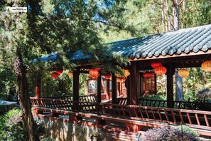 A traditional wooden pavilion with a tiled roof, surrounded by lush greenery and trees. - Rung Thong Nui Voi Villa & Resort (Hiep Thanh)