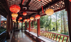 A covered walkway with red lanterns, wooden pillars, and a view of a forest. - Rung Thong Nui Voi Villa & Resort (Duc Trong)