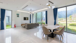 Ein geräumiges Wohnzimmer mit großem Esstisch, einer Couch und einem Fernseher.