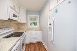 A kitchen with white cabinets, a microwave, an oven, and a refrigerator.
