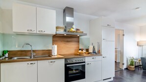 A modern kitchen with white cabinets, a wooden countertop, a stainless steel range hood, and a built-in oven. - Apartment 'Fewo-Keinath' with Wi-Fi (Winterlingen)