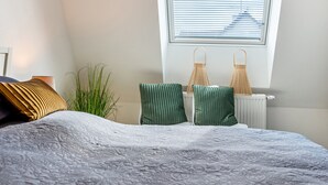 A bedroom with a bed, two pillows, a radiator, and a window with blinds. - Apartment 'Fewo-Keinath' with Wi-Fi (Winterlingen)