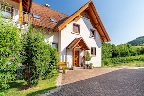 Une maison à deux étages, dotée d’un toit en pente, de poutres en bois et d’une allée pavée.