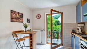 Una cocina con comedor, vista a zonas verdes y una mesa de madera con sillas.