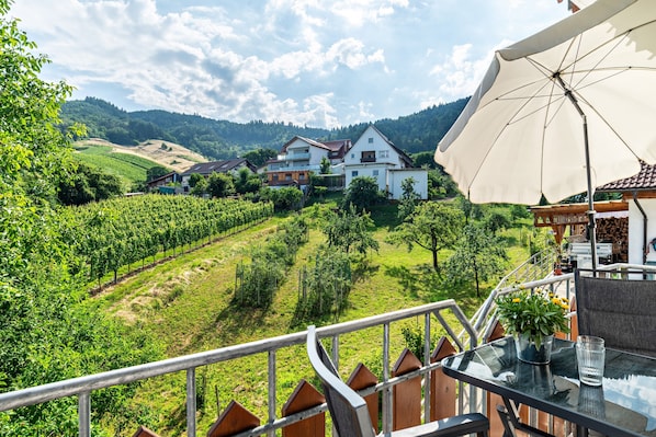 Un balcon avec une table, une plante en pot et un verre d’eau.