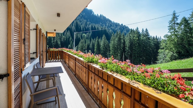 A balcony with wooden railings, a table, and chairs, overlooking a forested area with a mountain in the background. - Apartment 'Bachwiesl Hof Ocker' with Mountain View, Shared Terrace and Wi-Fi (Proves)