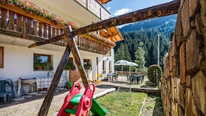 A children's play area with a slide, a wooden play structure, and a seating area with tables and chairs. - Apartment 'Bachwiesl Hof Ocker' with Mountain View, Shared Terrace and Wi-Fi (Proves)