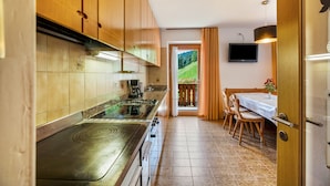 A kitchen with wooden cabinets, a stove, and a dining area with a table and chairs. - Apartment 'Bachwiesl Hof Ocker' with Mountain View, Shared Terrace and Wi-Fi (Proves)