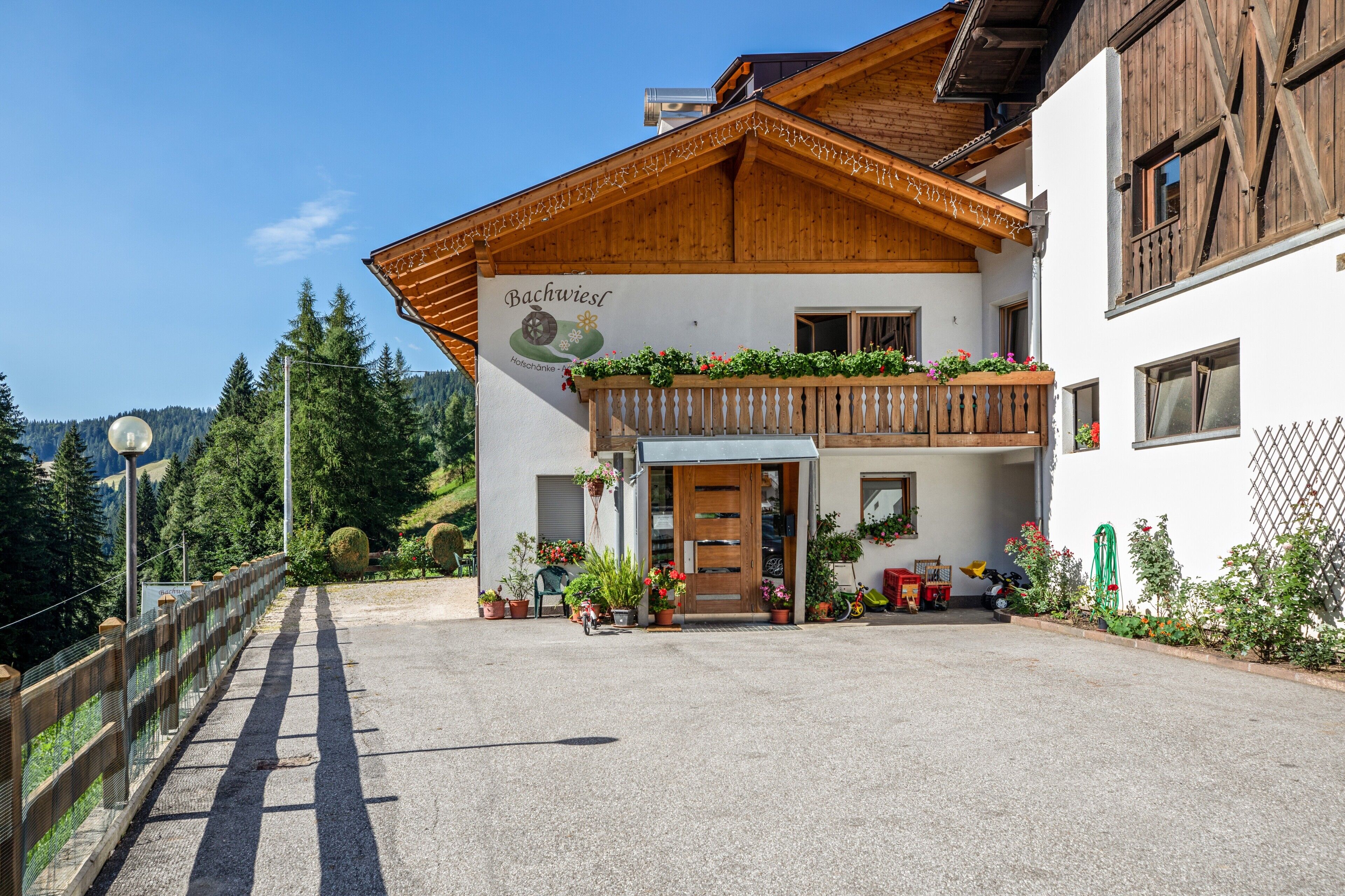 Un bâtiment traditionnel en bois, doté d’un balcon, de plantes en pot et d’une enseigne indiquant qu’il s’agit d’un restaurant.