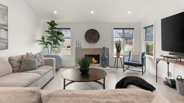 A modern living room with a sofa, a round coffee table, a TV, and a fireplace. - Urban Beach House in Downtown Huntington Beach (Huntington Beach)