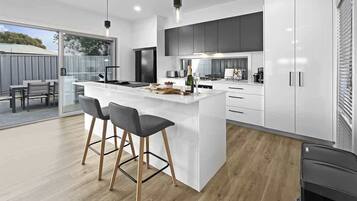 A modern kitchen with a central island, bar stools, and a dining area with a table and chairs.