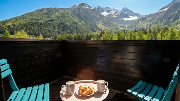 En træterrasse med to stole og et bord, et fad med croissanter og to kopper.