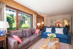 A living room with two sofas, a coffee table, and a window with curtains.