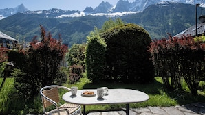Un tavolo rotondo con un piatto di cibo e due tazze, allestito all'aperto con vista sulle montagne.