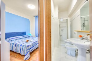 A hotel room with a bed, a shower, and a bathroom with a sink and toilet.