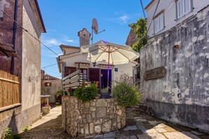 A narrow street with a building featuring a stone wall entrance, a satellite dish, and a sign reading 'BEJSKI TOS'. - Beli Old Town 2BR Apartment /w Terrace, Beli, Croatia (Beli)