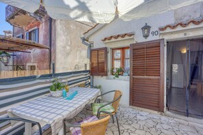 Relax in the charming outdoor seating area with a table, wicker chairs, and a shaded umbrella.