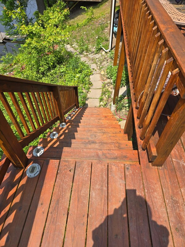 A wooden deck with a metal railing leading to a stone pathway. - Spacious 5 Bedroom Cabin Riverfront/Black Lake Access (Hammond)
