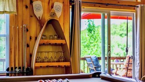 A pool table with cue sticks, a shelf with wine glasses, and a view of the outdoors through a glass door. - Spacious 5 Bedroom Cabin Riverfront/Black Lake Access (Hammond)