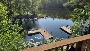 A lake with two wooden docks, surrounded by dense trees and greenery. - Spacious 5 Bedroom Cabin Riverfront/Black Lake Access (Hammond)