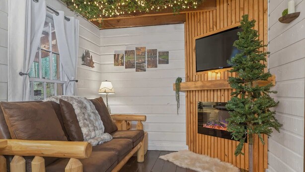 A cozy living room with a wooden sofa, a fireplace, and a small Christmas tree. - Good Times cabin at Saluda Grade Cabins! (Saluda)